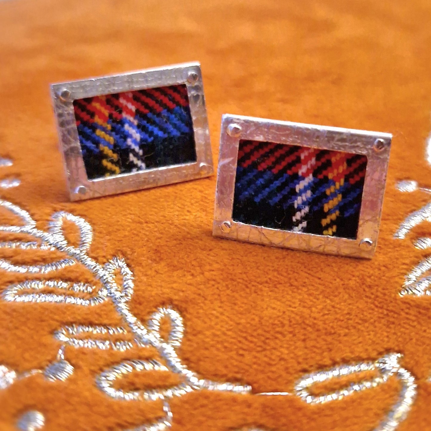 A pair of hallmarked sterling silver cufflinks with a rectangular shape, featuring Royal Stewart tartan fabric inlay, and secured with sterling silver swivel backs.