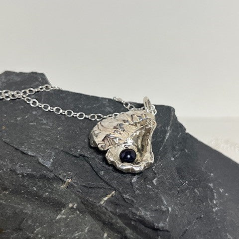 Close-up of double sterling silver oyster shell pendant on an 18-inch chain showing the unique pearl inside.