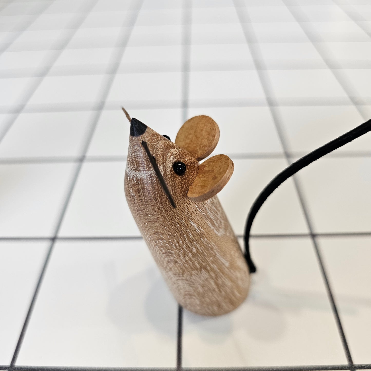 A decorative mouse, uniquely carved from local wood, standing upright with small eyes, ears, whiskers and a leather tail
