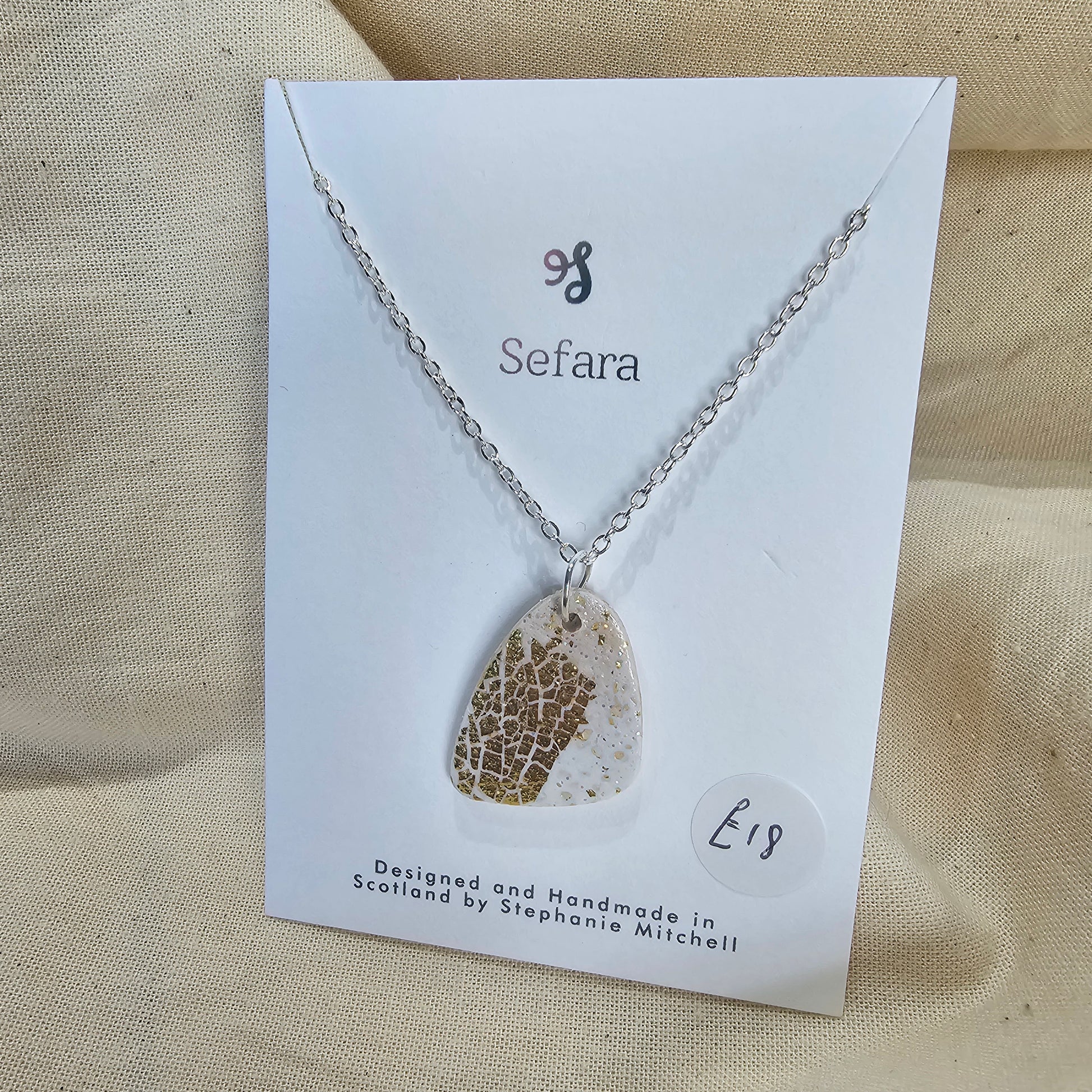 Handmade cream polymer clay pebble shaped pendant on 18-inch silver plated chain by Sefara Jewellery. Gold leaf design.