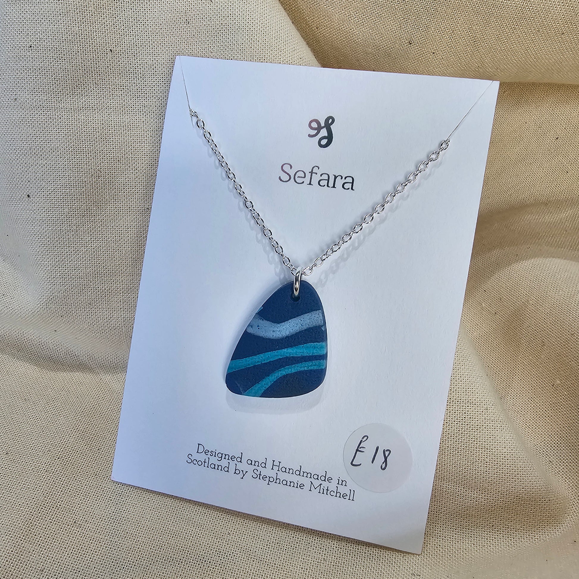 Handmade blue polymer clay pebble shaped pendant on 18-inch silver plated chain by Sefara Jewellery. Striped design.
