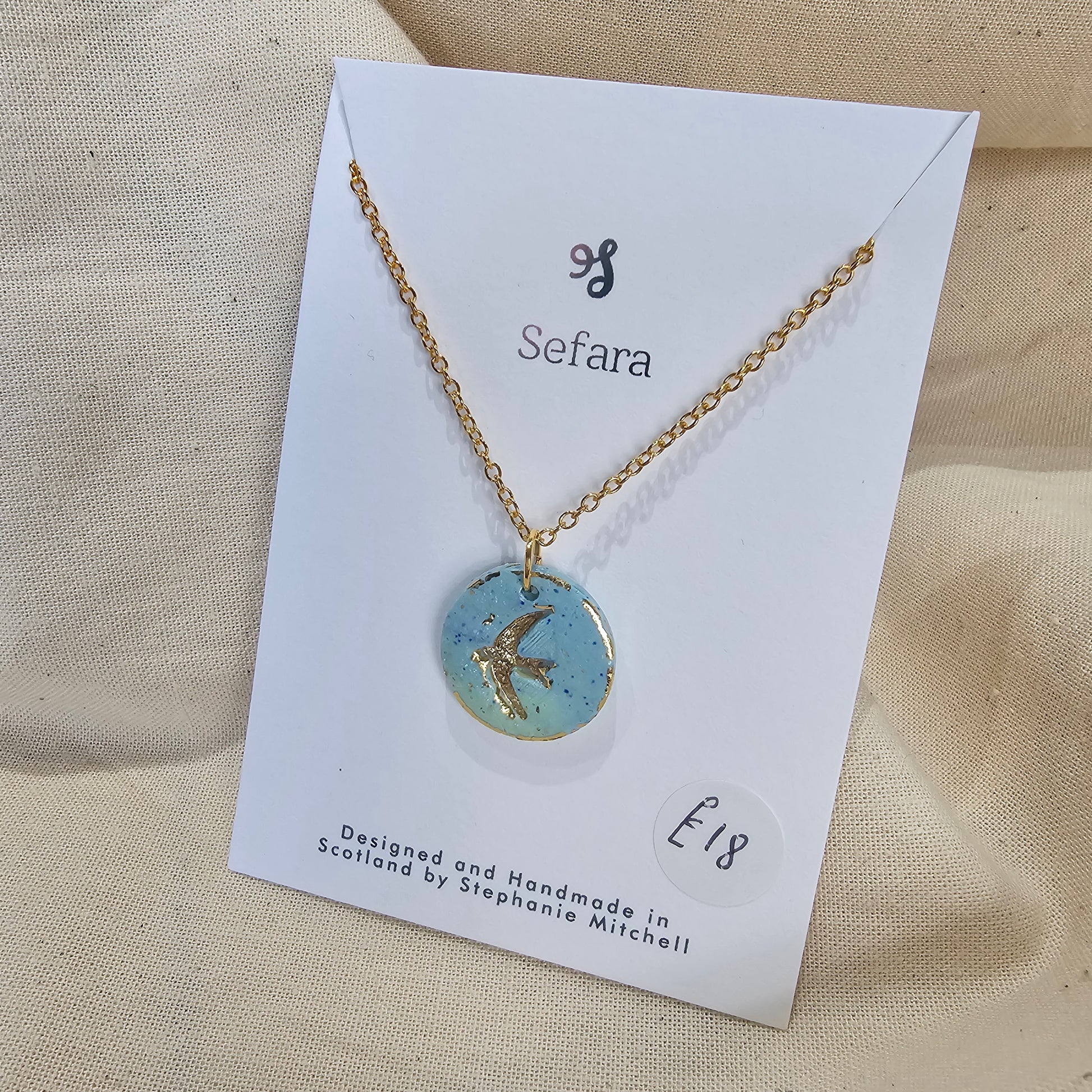 Handmade aqua polymer clay circle pendant on 18-inch gold plated chain by Sefara Jewellery. Swallow design.