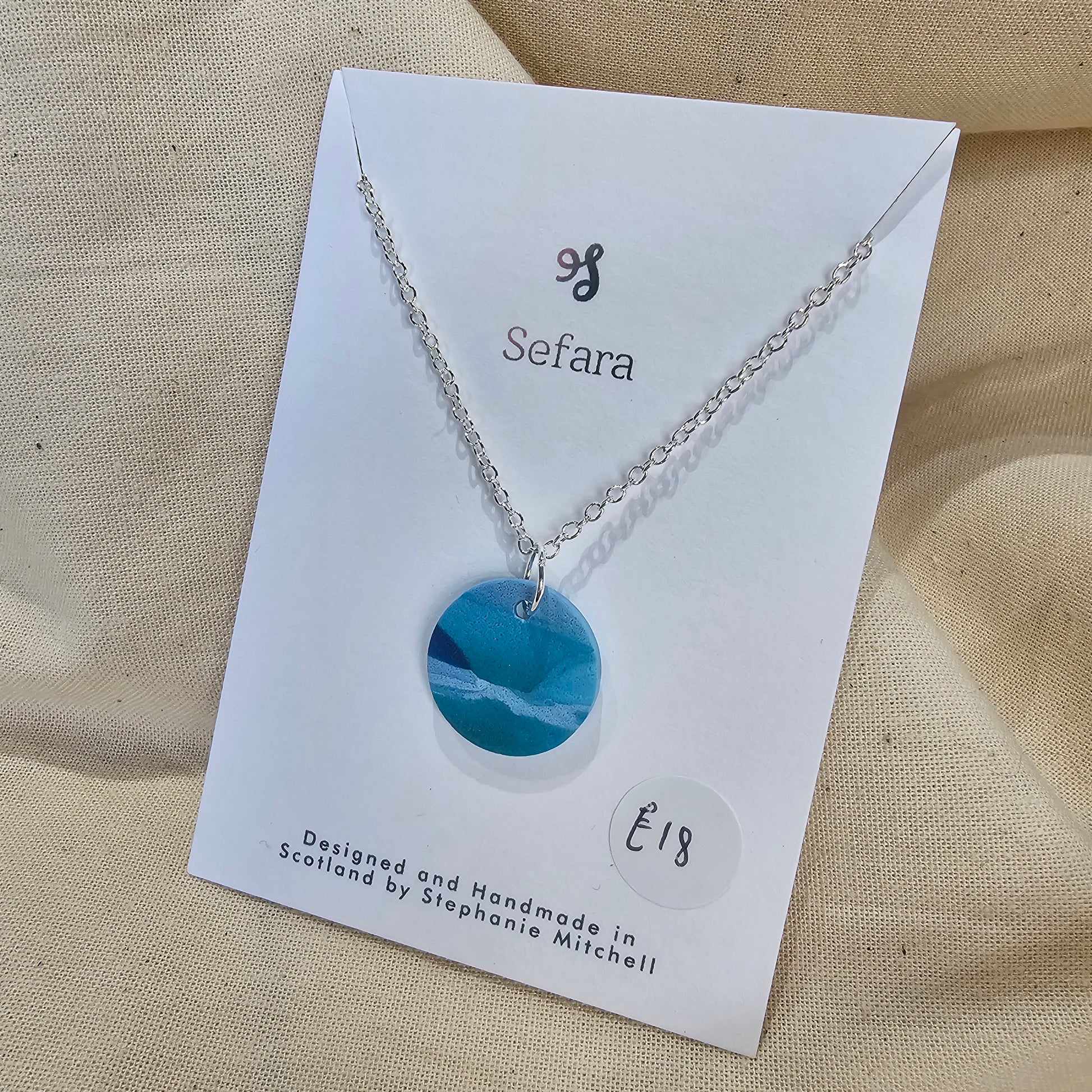 Handmade blue polymer clay circle pendant on 18-inch silver chain by Sefara Jewellery. Nautical design.