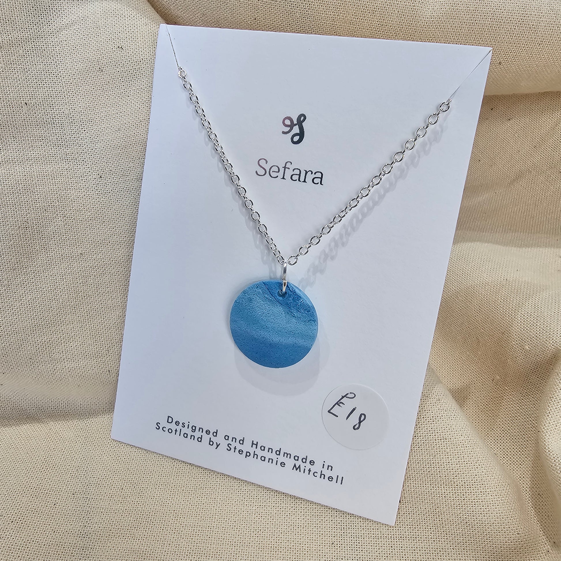 Handmade blue polymer clay circle pendant on 18-inch silver plated chain by Sefara Jewellery. Nautical design.