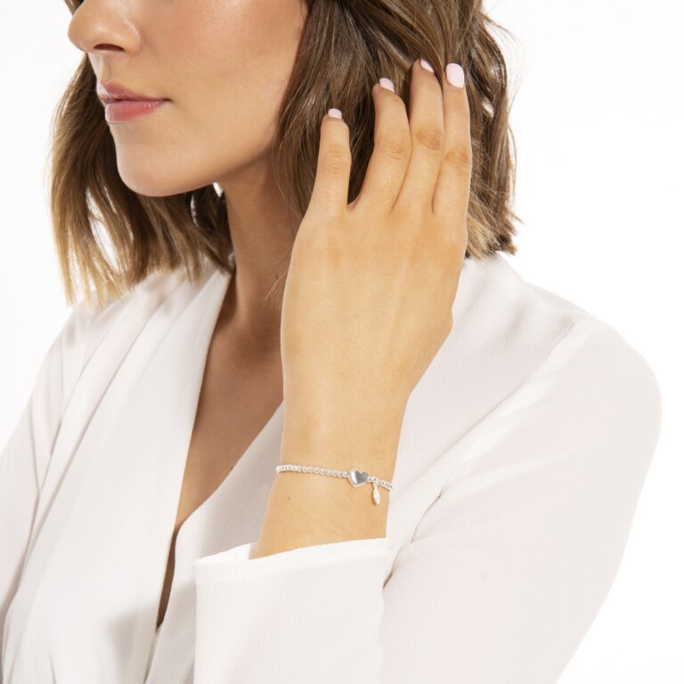 A silver plated beaded stretch bracelet with a heart-shaped charm