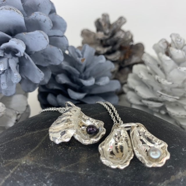 Close-up of double sterling silver oyster shell pendants on 18-inch chains showing the unique pearls inside.