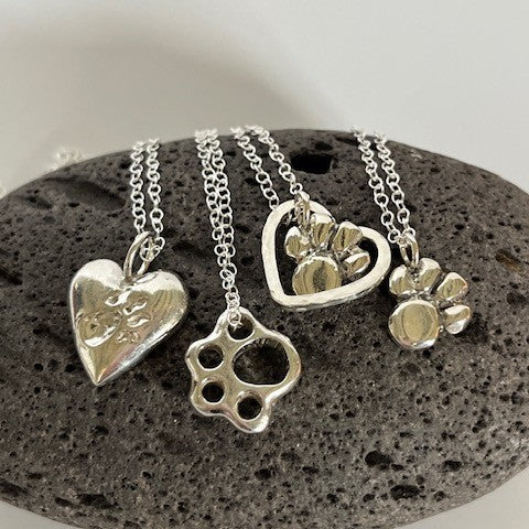 Collection of solid sterling silver paw print pendants suspended on an 18-inch silver chains.