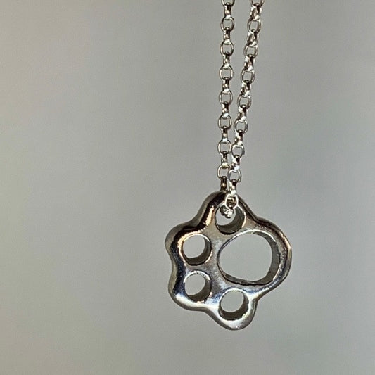 A solid silver pendant in the shape of a paw print, attached to an 18-inch silver chain.