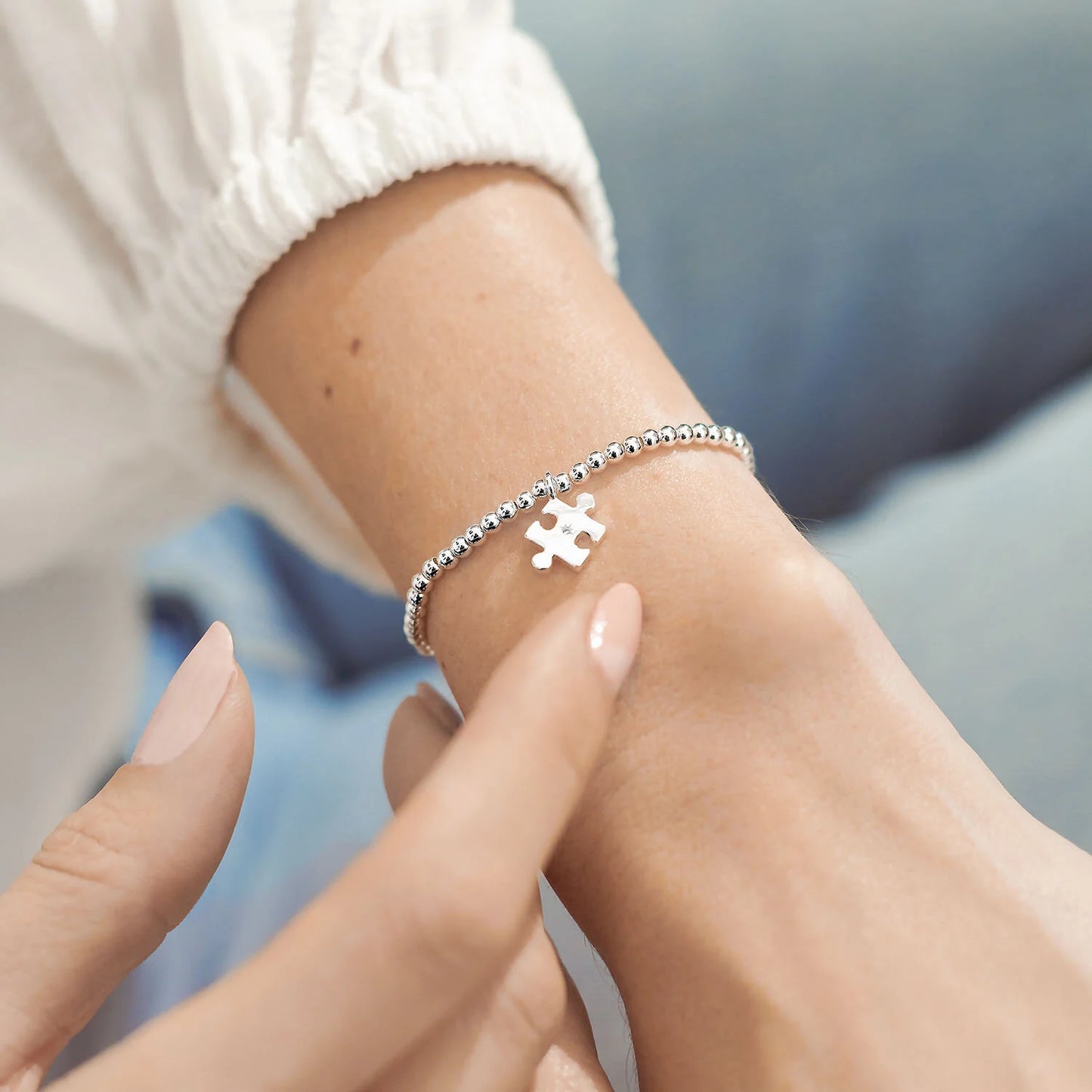 A silver plated stretch beaded bracelet with a puzzle piece charm