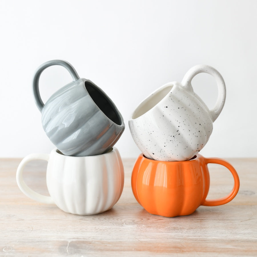 Assortment of ceramic pumpkin-shaped mugs including white, orange and grey