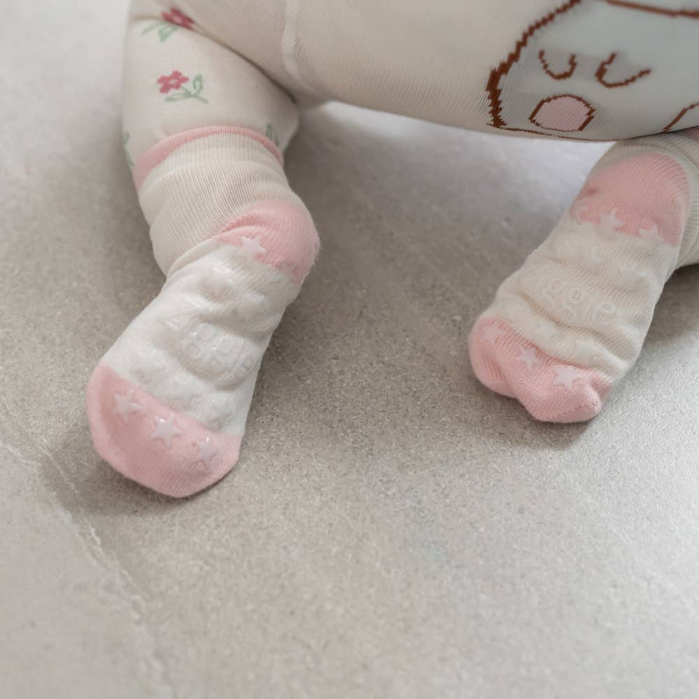 Baby's feet wearing pink cotton baby socks with bunny design, anti-slip soles and ribbed cuffs