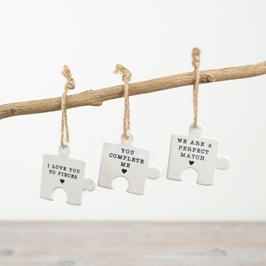 Small hanging ceramic jigsaw puzzle pieces with words and hearts.