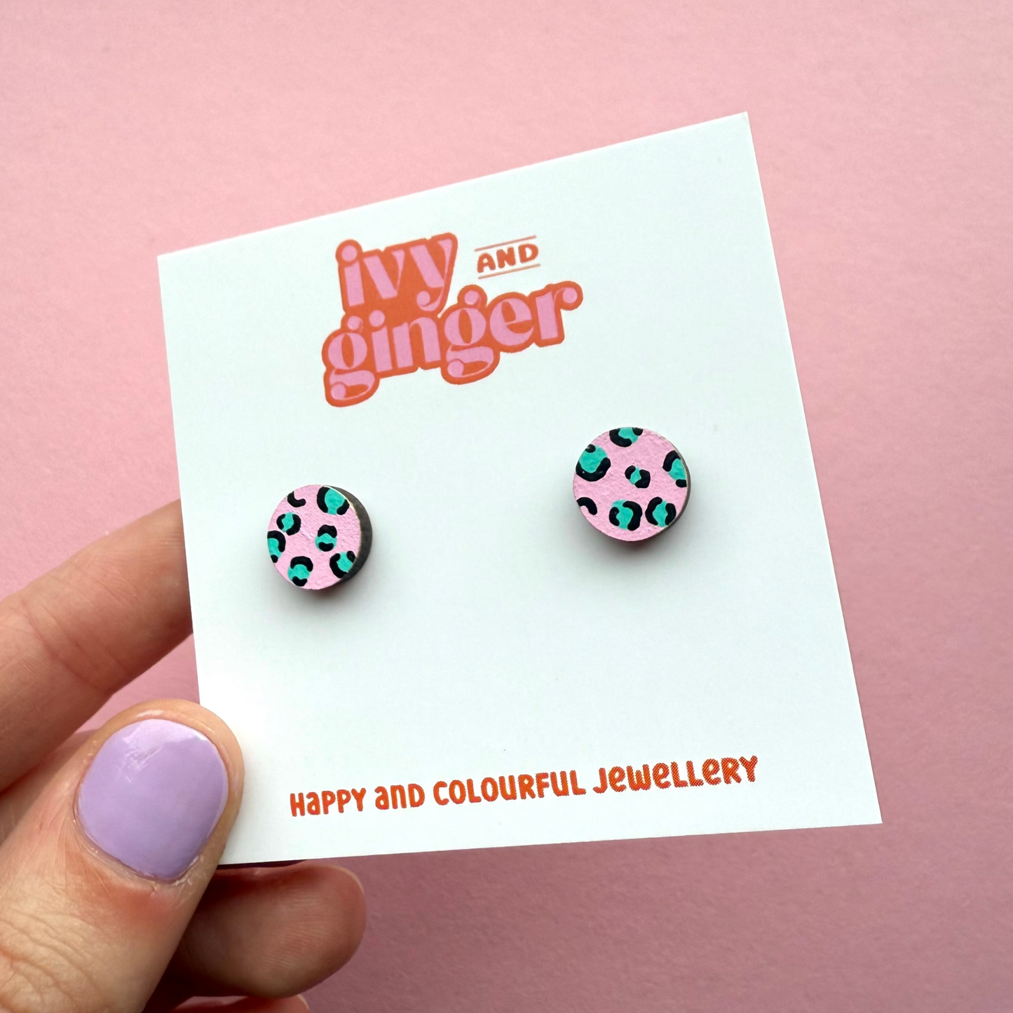 Pink circle stud earrings with teal and black leopard print, hand painted FSC wood, 10mm, surgical steel posts, bold and playful design.