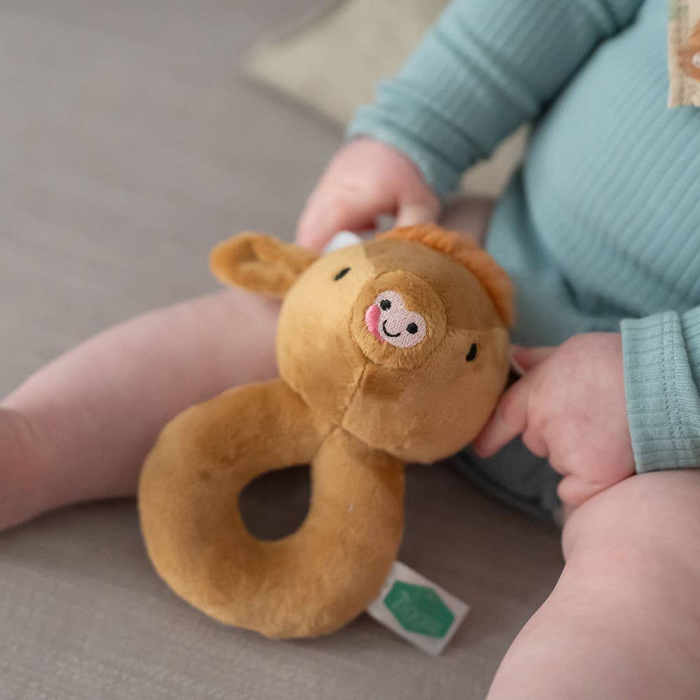 Child holding a Soft Highland Cow plush baby rattle with gentle sensory sound, perfect for newborns