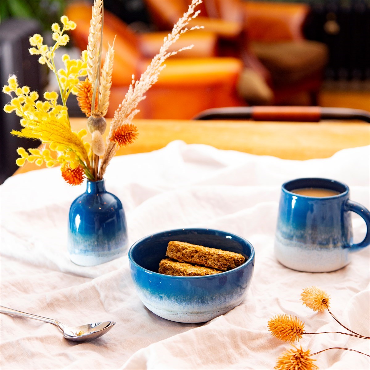 A stoneware mug, bowl and mini vase featuring a blue ombre colour transition achieved with a reactive glaze