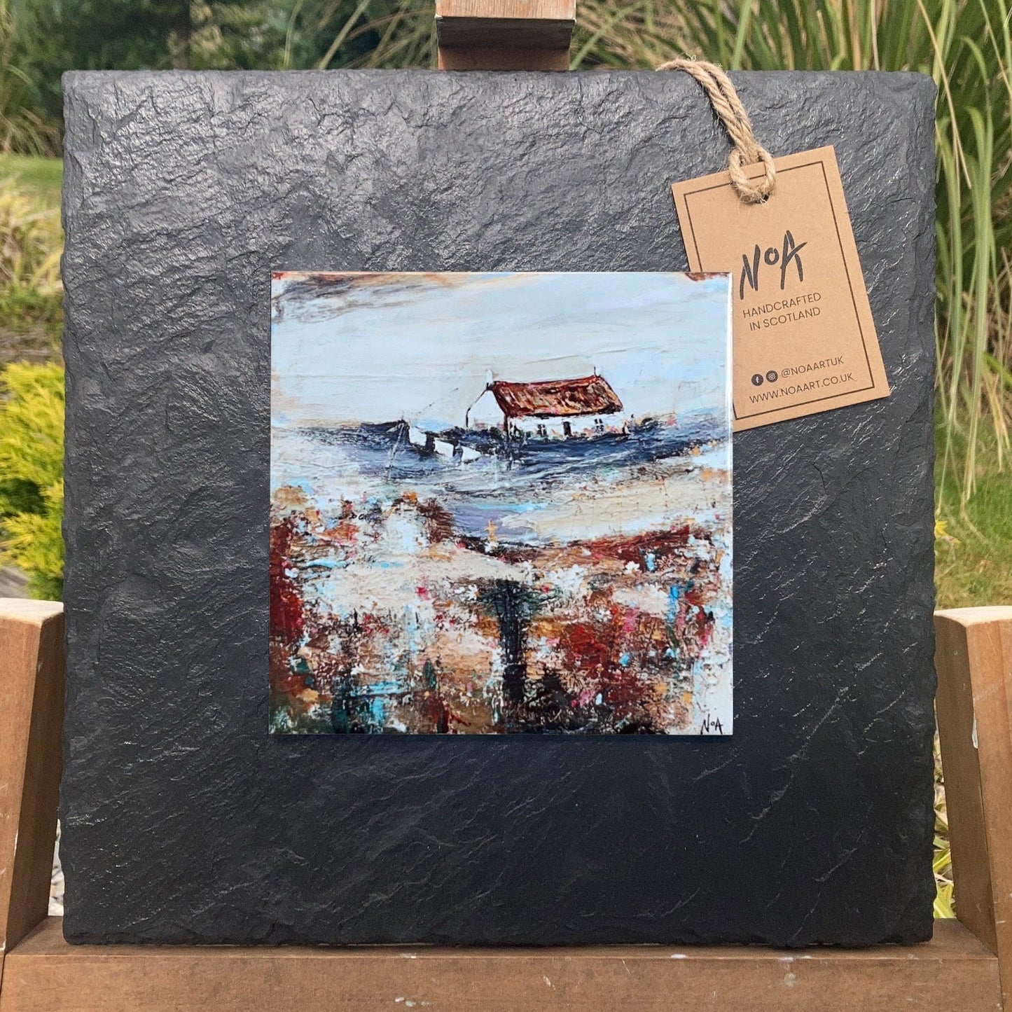 A ceramic tile print of a colourful painting titled 'Easter Cottage', showing a small house nestled in the Scottish Highlands, available mounted on natural slate or framed.