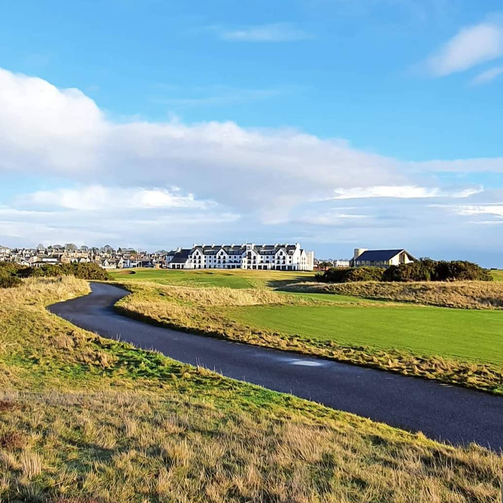 Golf course with a path and hotel under a blue sky