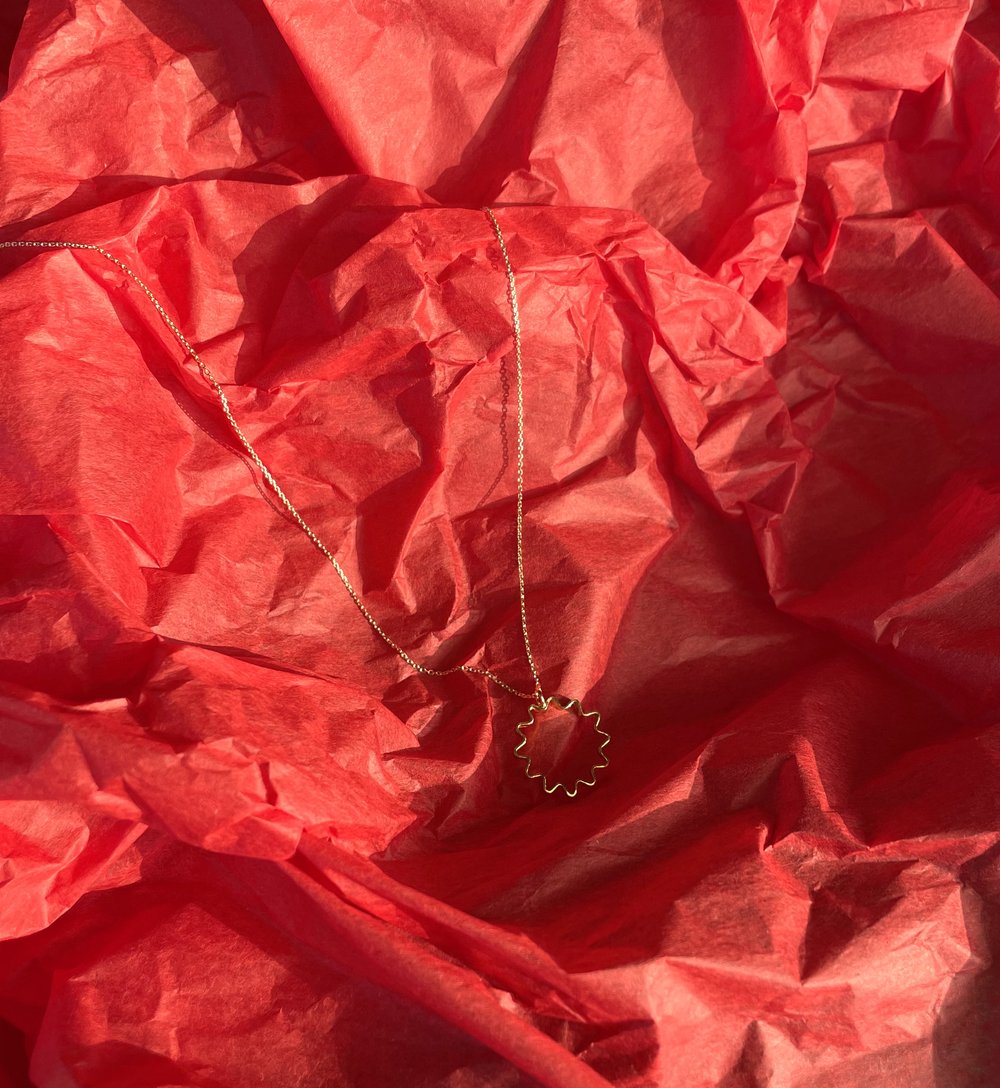 Mini ondulée pendant necklace in recycled sterling silver with silver chain, handmade by Olivia Taylor in Glasgow, lying on red tissue paper