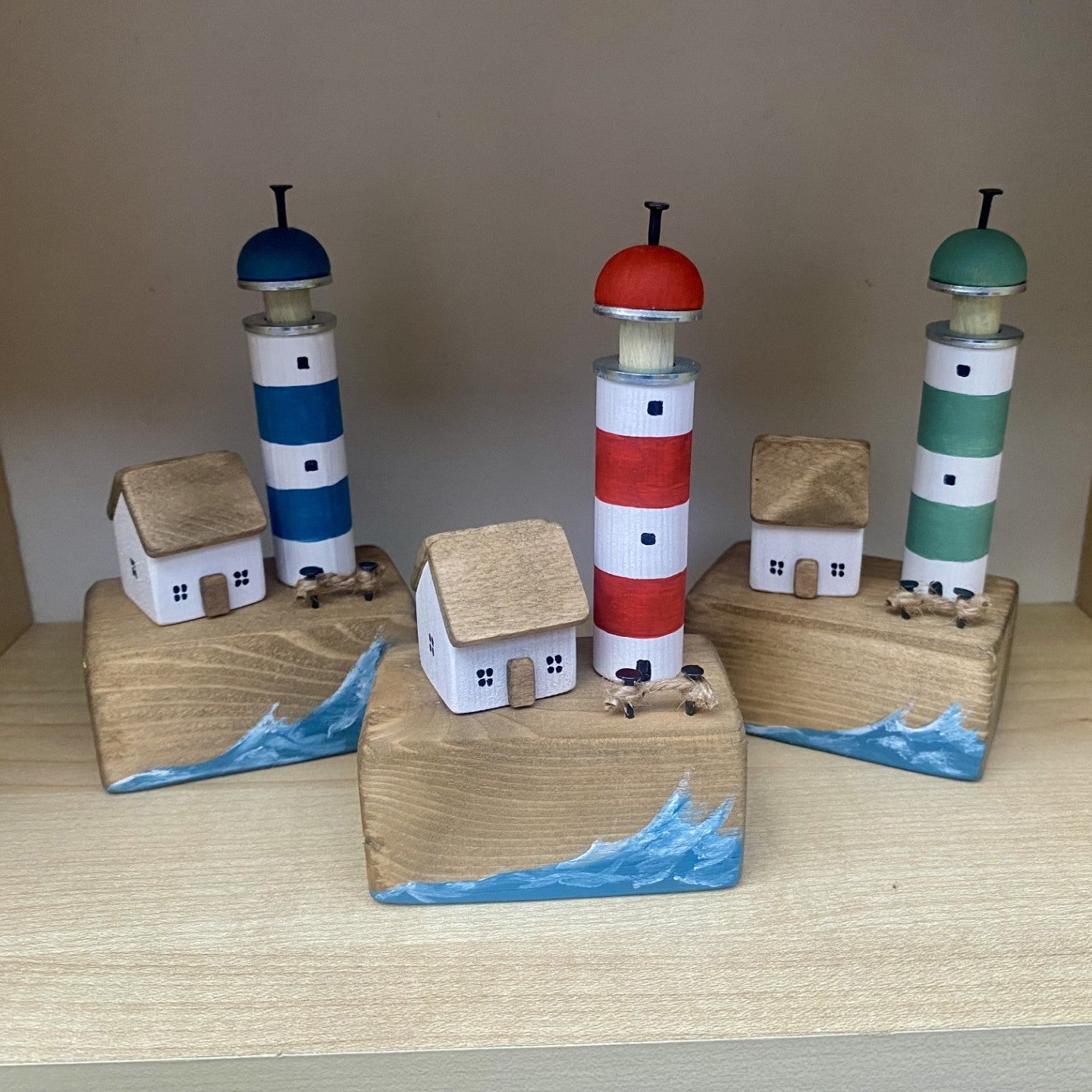 Handcrafted wooden lighthouse and cottage ornaments with nautical rope and metal details in red, green, or blue