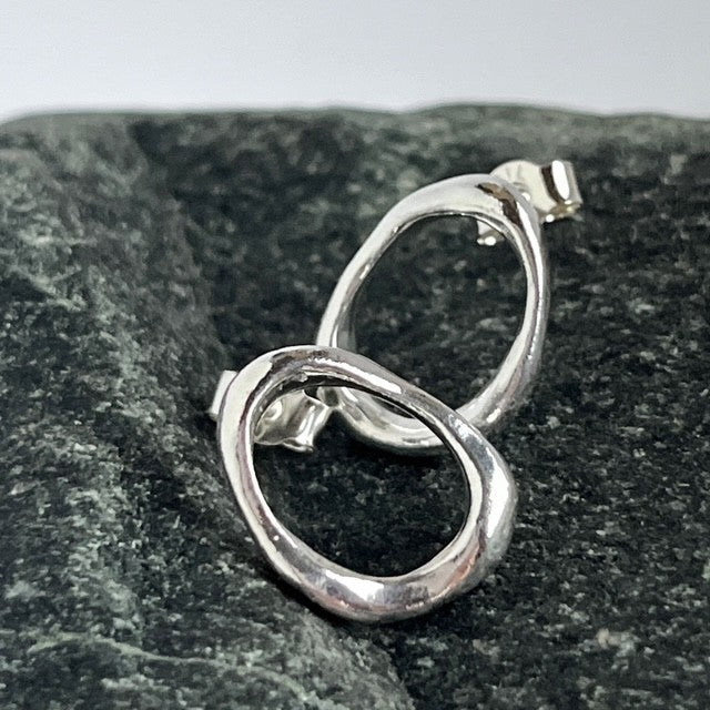 Close-up of a pair of minimalist solid sterling silver pebble stud earrings on posts