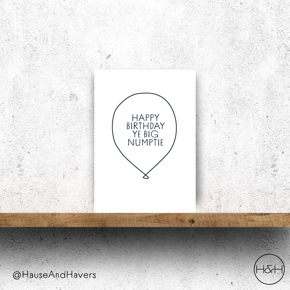 A vertically folded greeting card with the Scottish phrase "Happy Birthday Ye Big Numptie" in a modern, hand-designed style and balloon graphic.