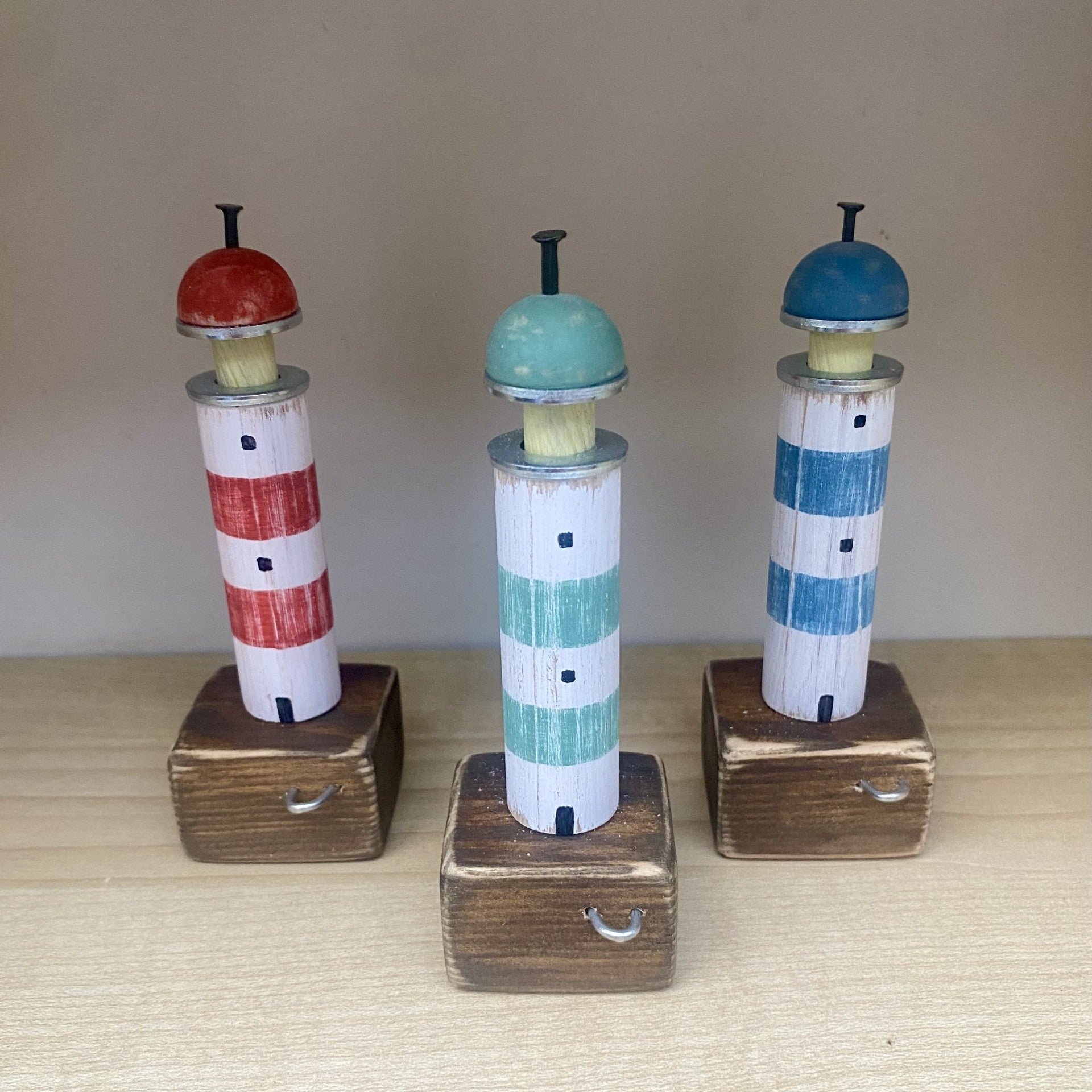 Handcrafted wooden lighthouse ornaments with rustic metal and rope details in Blue, Green, or Red