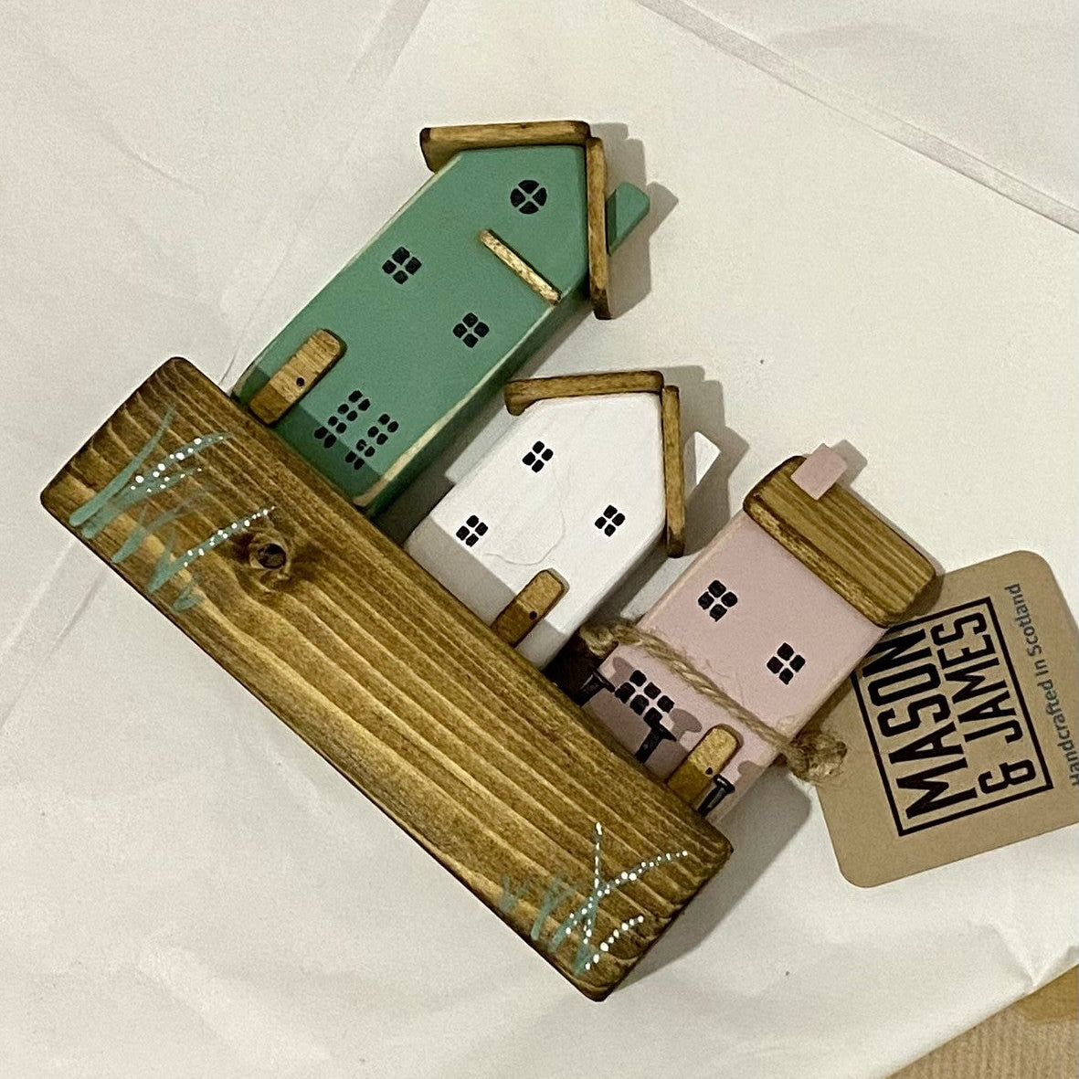 Handcrafted trio of wooden houses on block with rustic metal details in green, pink, and white
