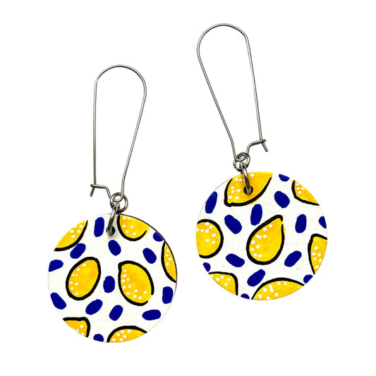 A pair of white lemon drop circle dangle earrings with silver hooks, featuring a pattern of yellow lemon-like shapes on a white background.