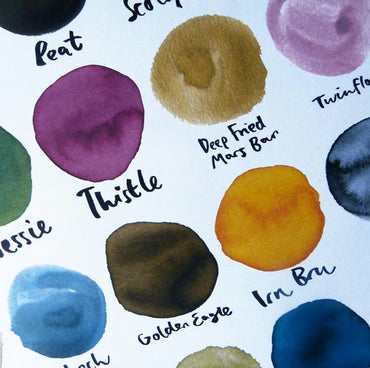 A colourful print by Emily Mackenzie titled '50 Shades of Scotland' featuring various circular inky colour swatches named after places or elements in Scotland with playful names like Deep Fried Mars Bar and Irn Bru