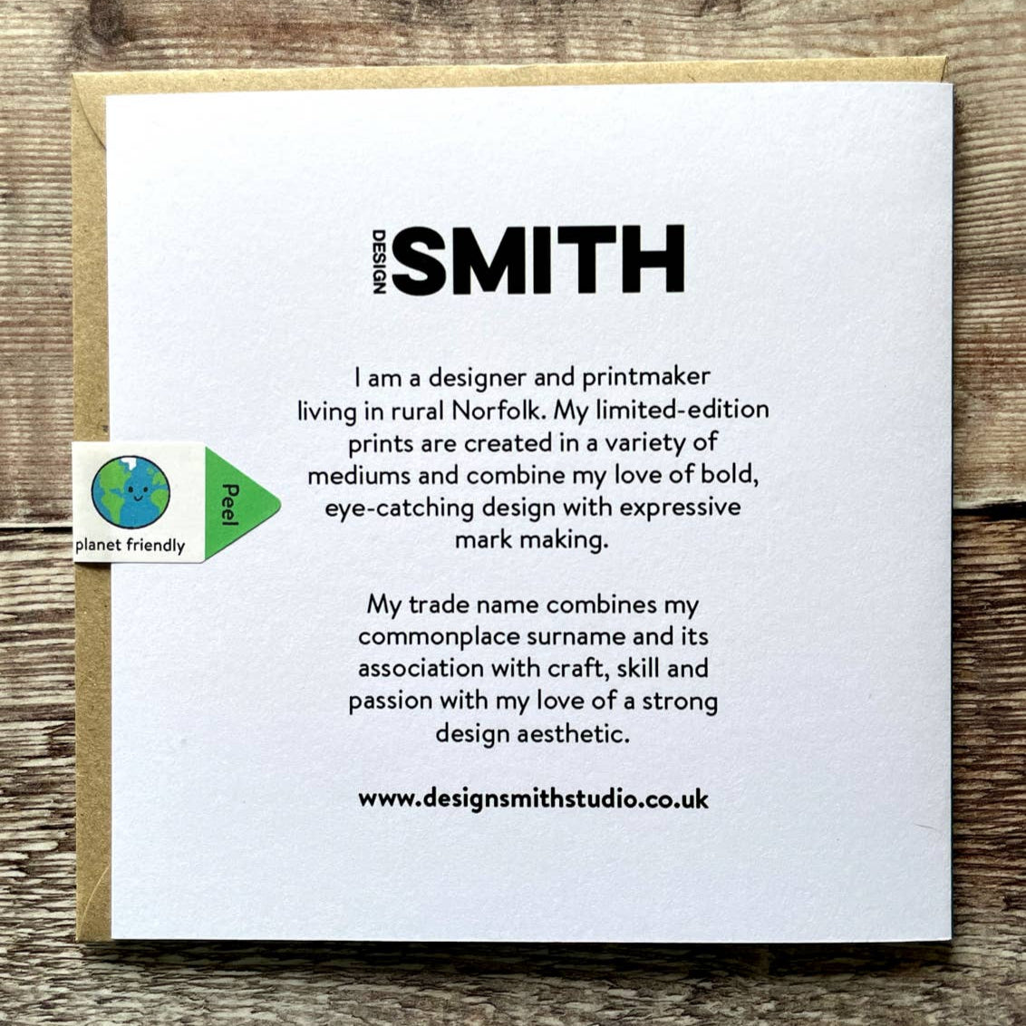 Rear of card with text about the designer and printmaker named Smith on a wooden surface