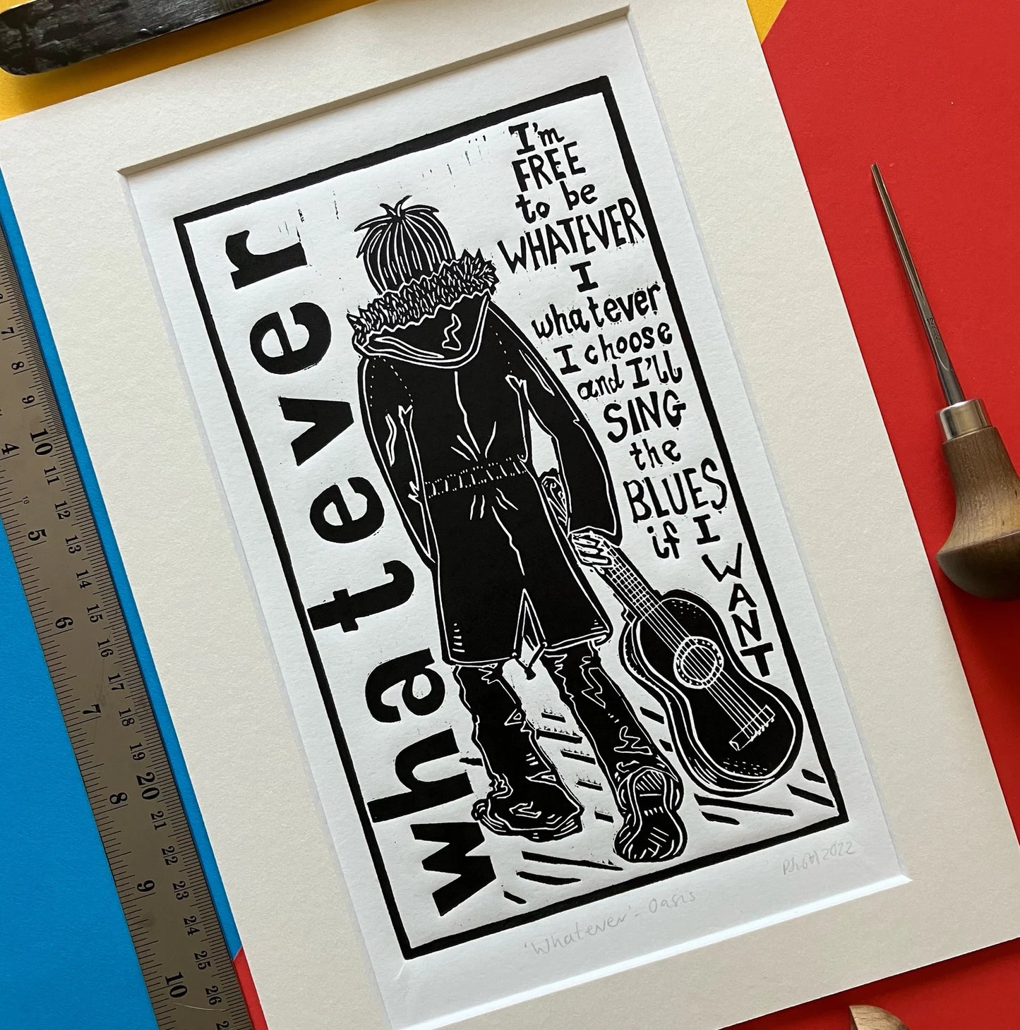 An original black and white linocut print featuring lyrics and imagery inspired by the Oasis song 'Whatever', mounted on antique white card.