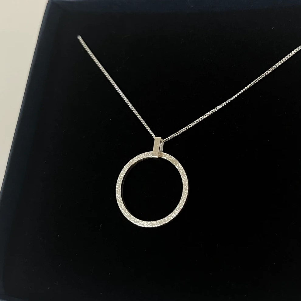 Large sterling silver pendant featuring a round textured disc connected by a small rectangular link, hanging on silver chain