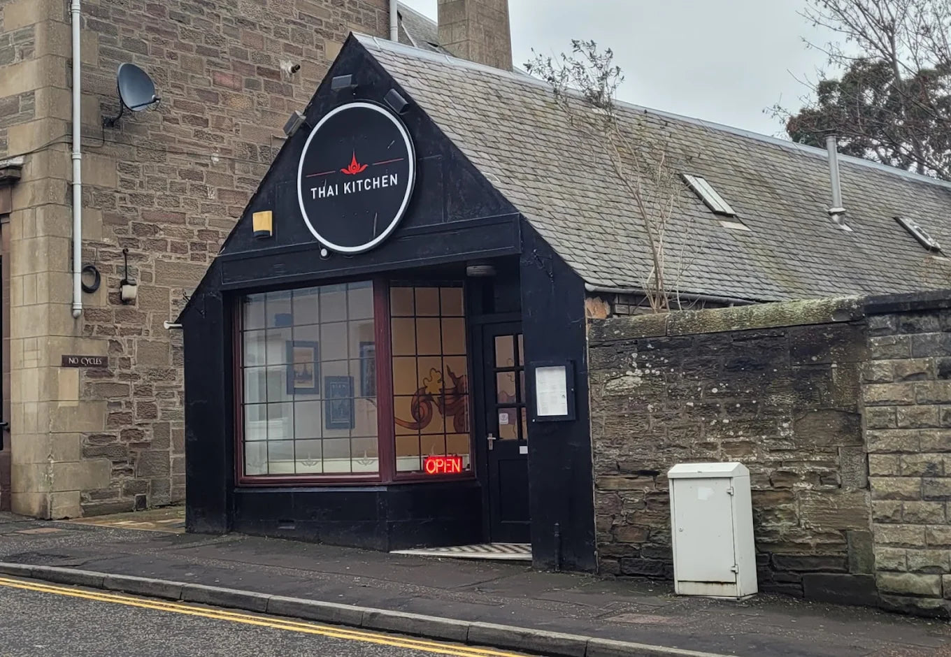 Black restaurant sign with 'Thai Kitchen' on a brick building