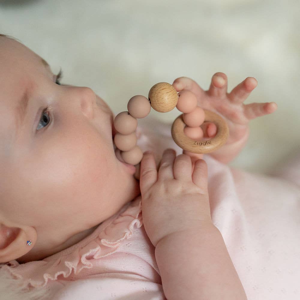 Baby holding a Ziggle wooden teether in Blush