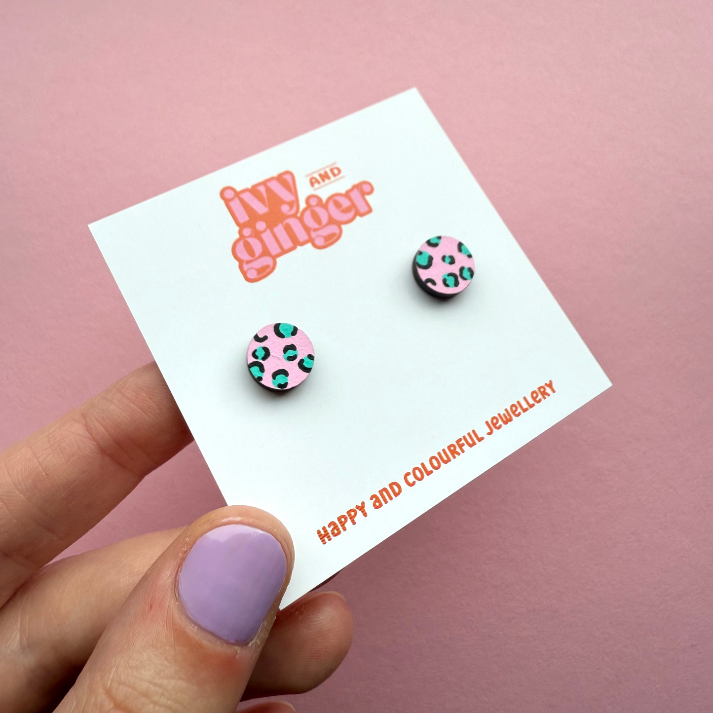 Pink circle stud earrings with teal and black leopard print, hand painted FSC wood, 10mm, surgical steel posts, bold and playful design.