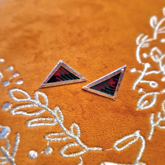 A pair of small, hallmarked sterling silver triangle stud earrings featuring a tartan fabric inlay and secured with sterling silver pins and scrolls.