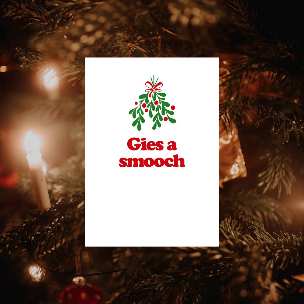An A6 vertically folded greeting card with a Scottish Christmas message "Gies A Smooch" and a mistletoe illustration.