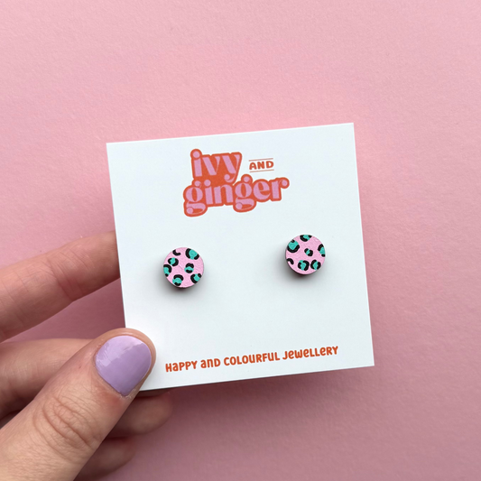 Pink circle stud earrings with teal and black leopard print, hand painted FSC wood, 10mm, surgical steel posts, bold and playful design.