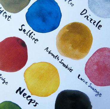 A colourful print by Emily Mackenzie titled '50 Shades of Scotland' featuring various circular inky colour swatches named after places or elements in Scotland with playful names like Arbroath Smokies and Neeps