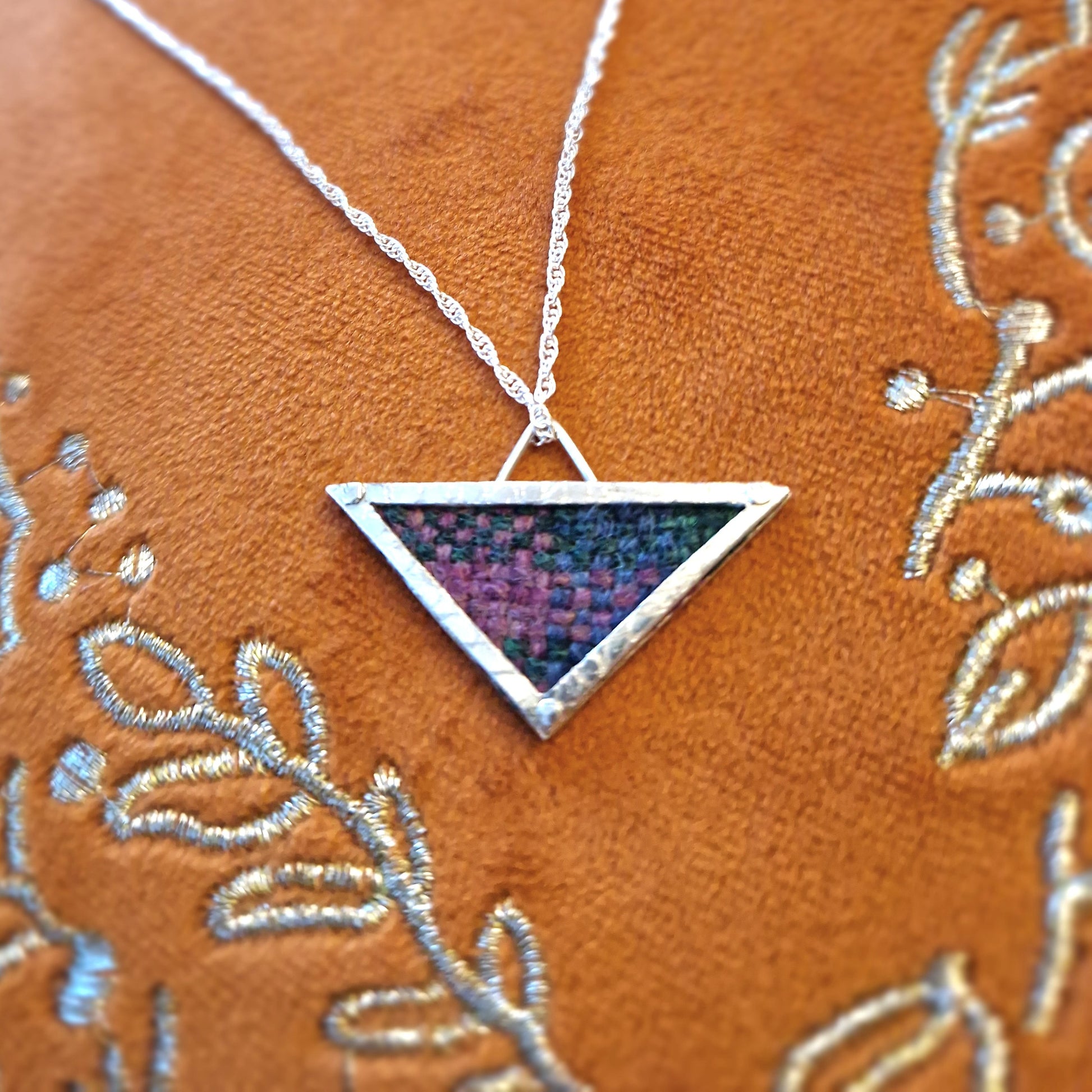 A hallmarked sterling silver triangle pendant showcasing a fabric tartan inlay, held by silver wire rivets, suspended from an 18-inch silver rope chain.