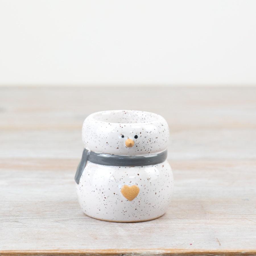 A small ceramic snowman tealight holder with a grey and white speckled finish.
