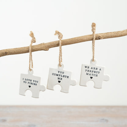 Small hanging ceramic jigsaw puzzle pieces with words and hearts.