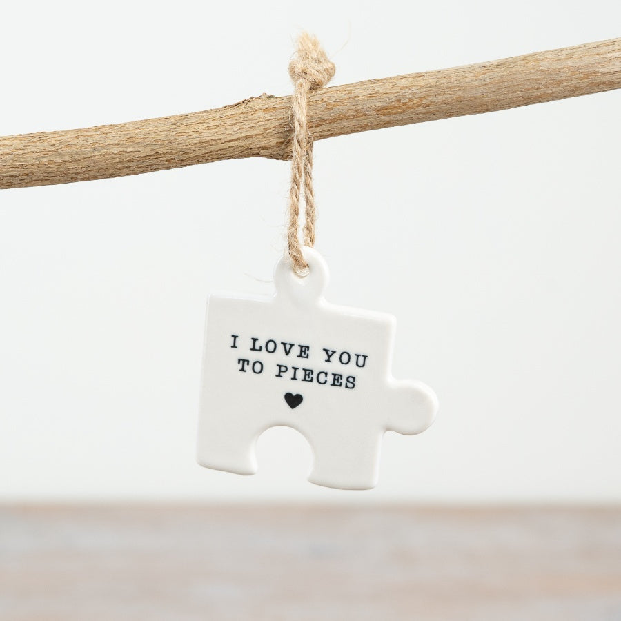 A small hanging ceramic jigsaw puzzle piece with the words "I love you to pieces" and a heart symbol.