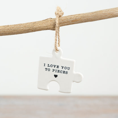 A small hanging ceramic jigsaw puzzle piece with the words "I love you to pieces" and a heart symbol.