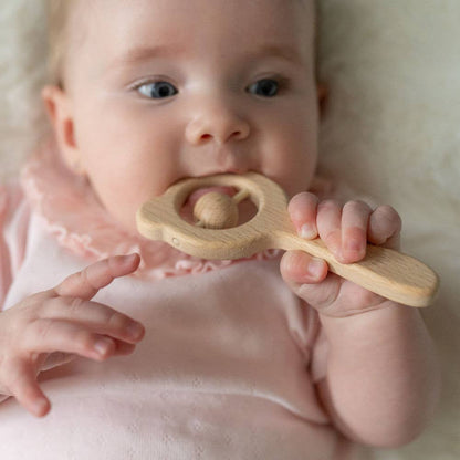 Baby holding a Ziggle wooden rattle