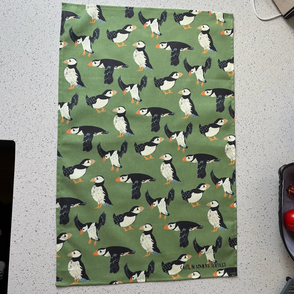 Tea towel with puffin pattern on a green background
