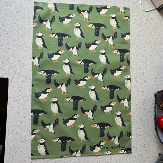 Tea towel with puffin pattern on a green background