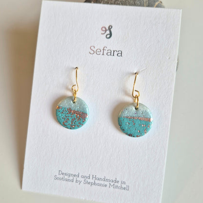Pair of turquoise and gold Sefara hook earrings on a branded card