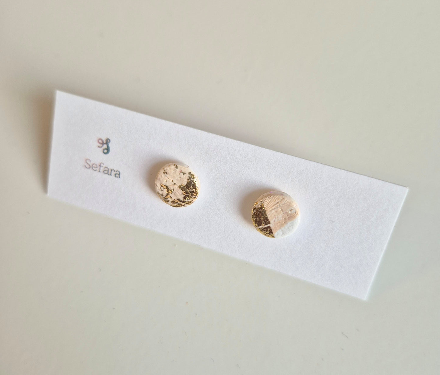 Beige White and Gold Sefara round stud earrings on a branded card