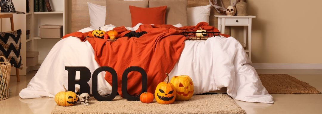 Halloween-themed bedroom with pumpkins, ghosts, and a 'BOO' sign on a bed.